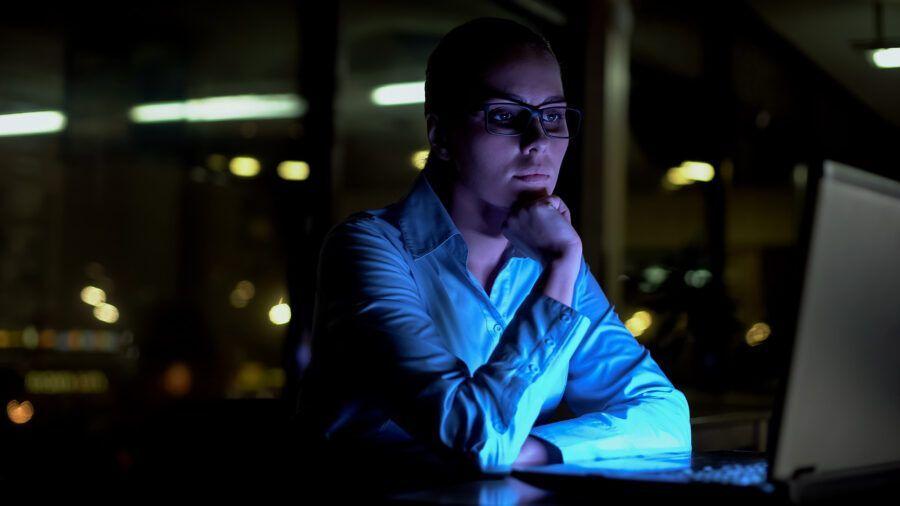 Female working extra hours at night in the office.