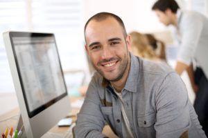 Cheerful guy sitting in front of desktop computer