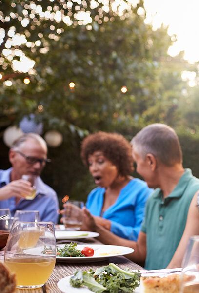 Group Of Mature Friends Enjoying Outdoor Meal In Backyard