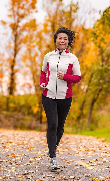 Asian woman running in wooded area