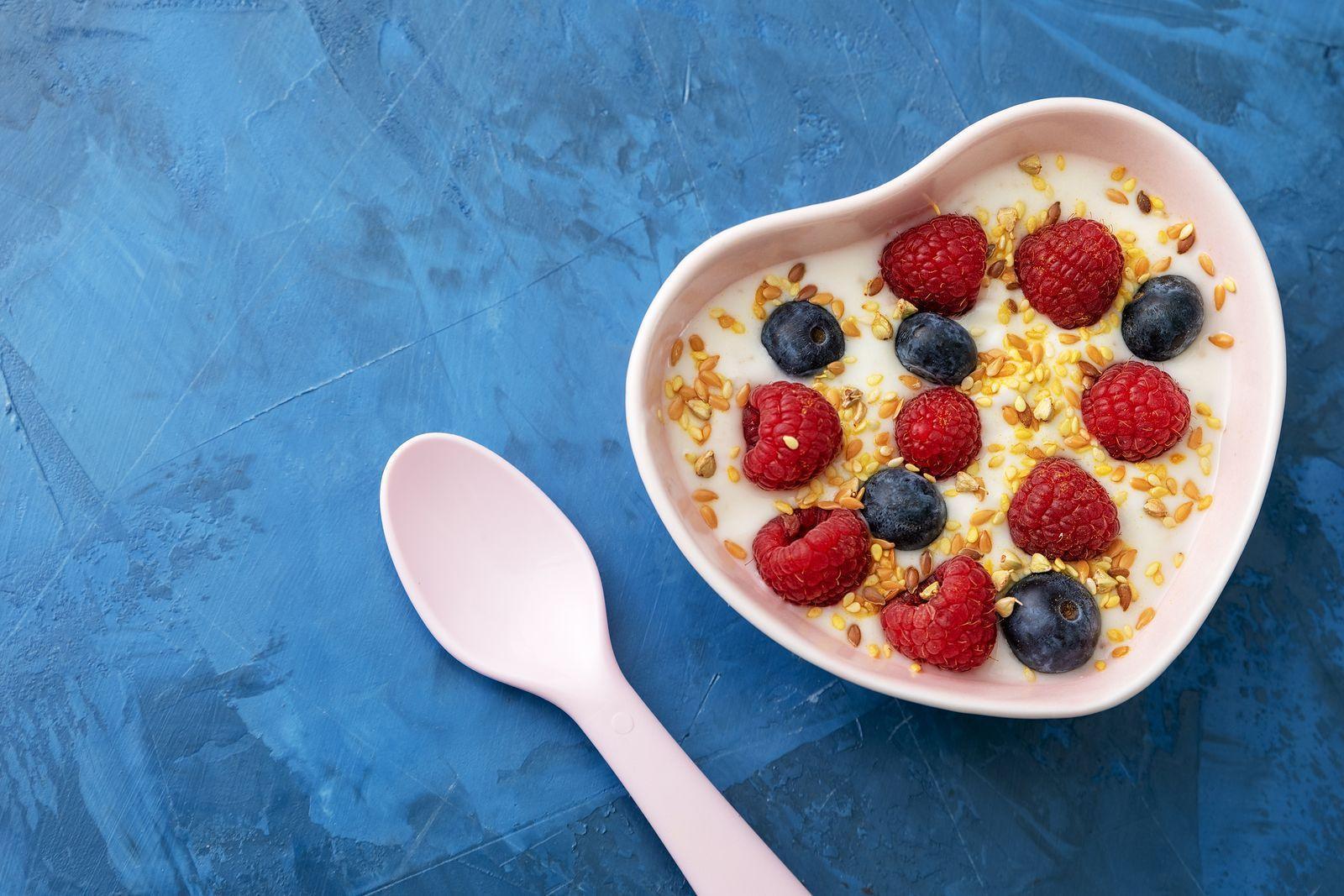 Sweet Creamy Dish with Berries Breakfast Top View. White Stylish Ceramic Spoon near Homemade Freshness Natural Bio Yoghurt with Grains of Seed, Blackberries and Raspberries in Pot Plate. Energy Meal