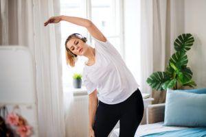 Young Woman Doing Exercise In Bedroom Indoors At Home.